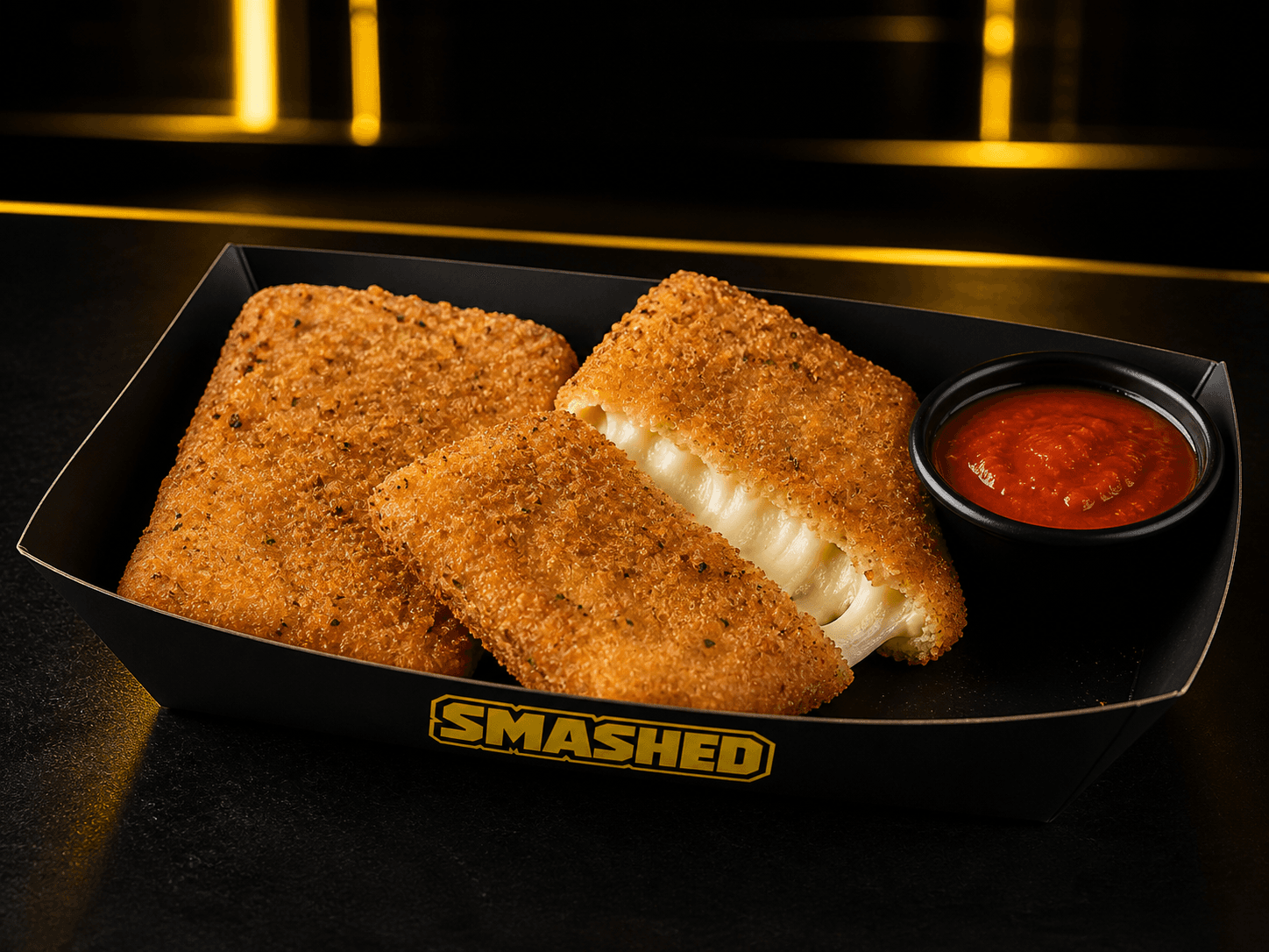 Crispy mozzarella patties with melted cheese in a black SMASHED box